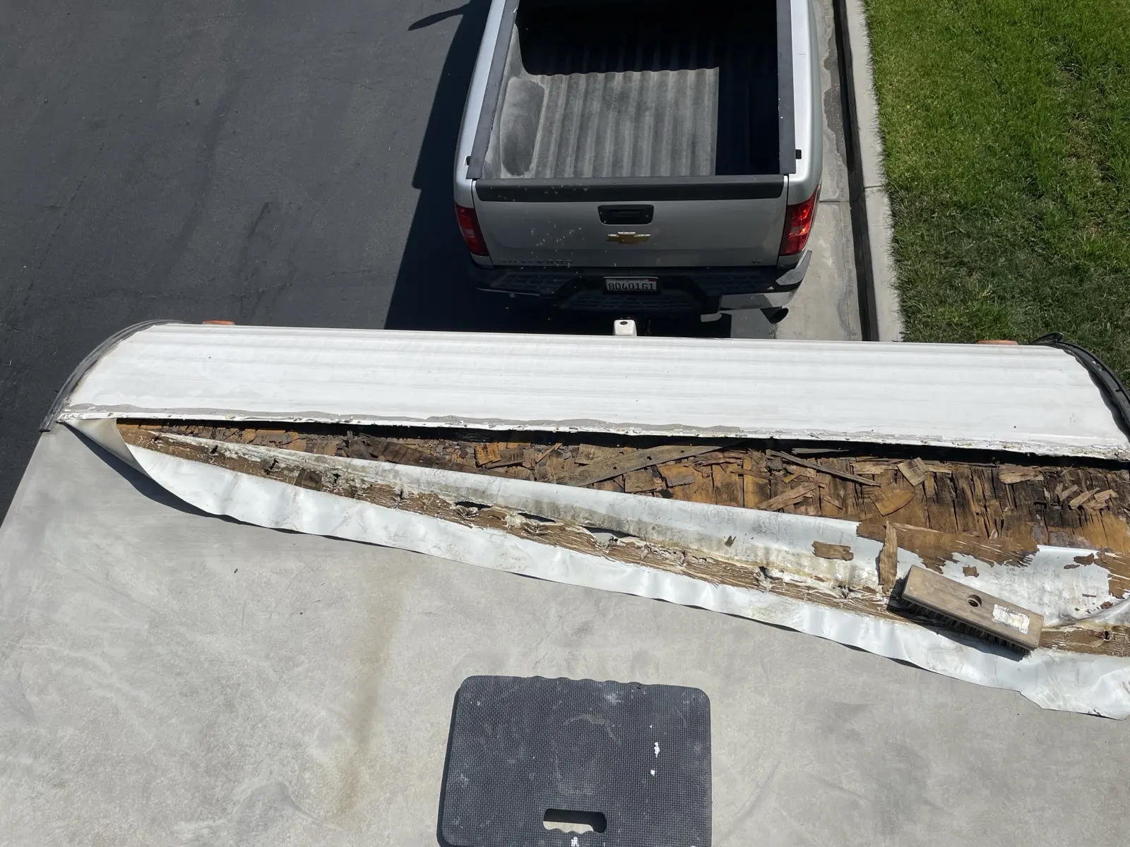 Peeled RV roof membrane at the front cap with rotten plywood underneath