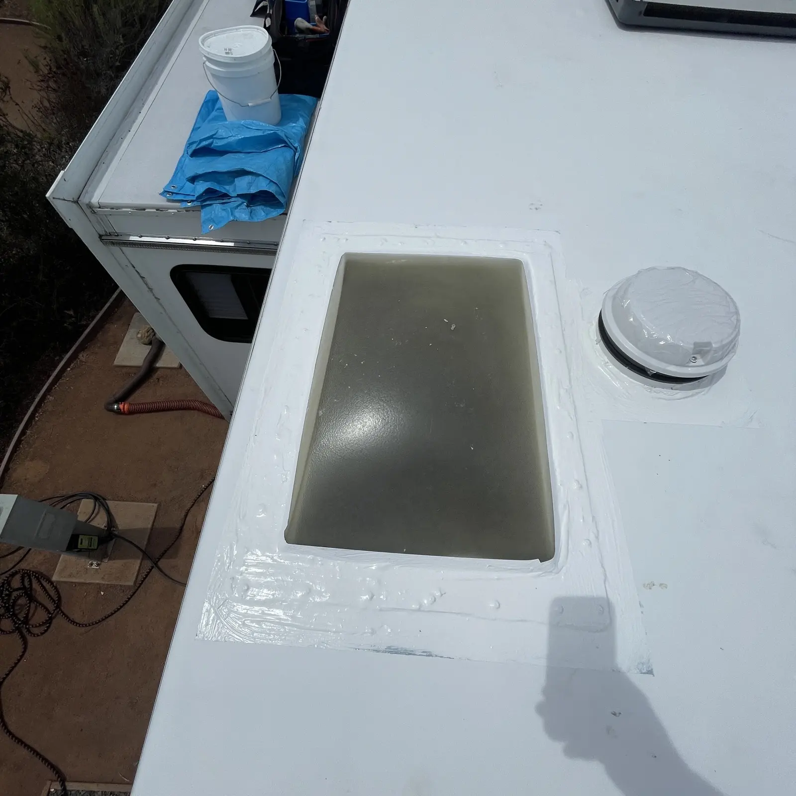 Skylight and plumbing vent resealed with new white sealant on a clean TPO roof