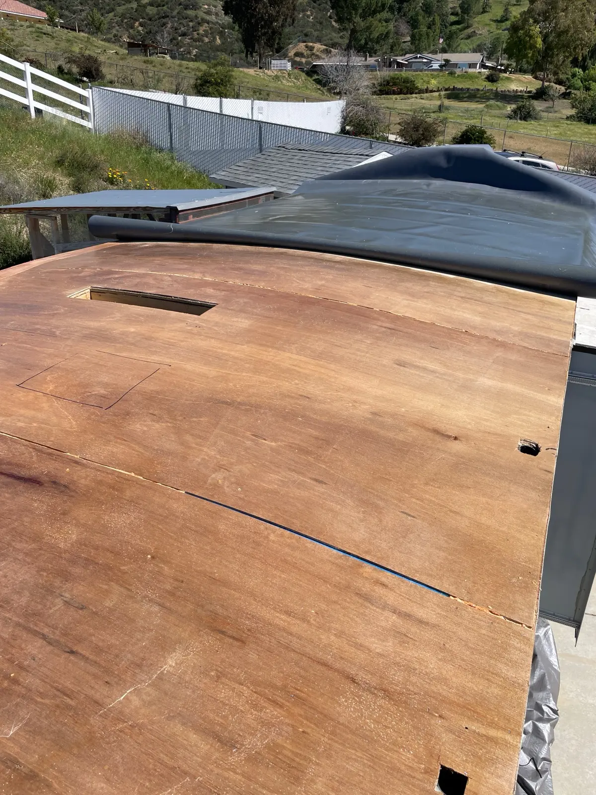 New plywood sheets installed on an RV roof deck with hatch openings cut