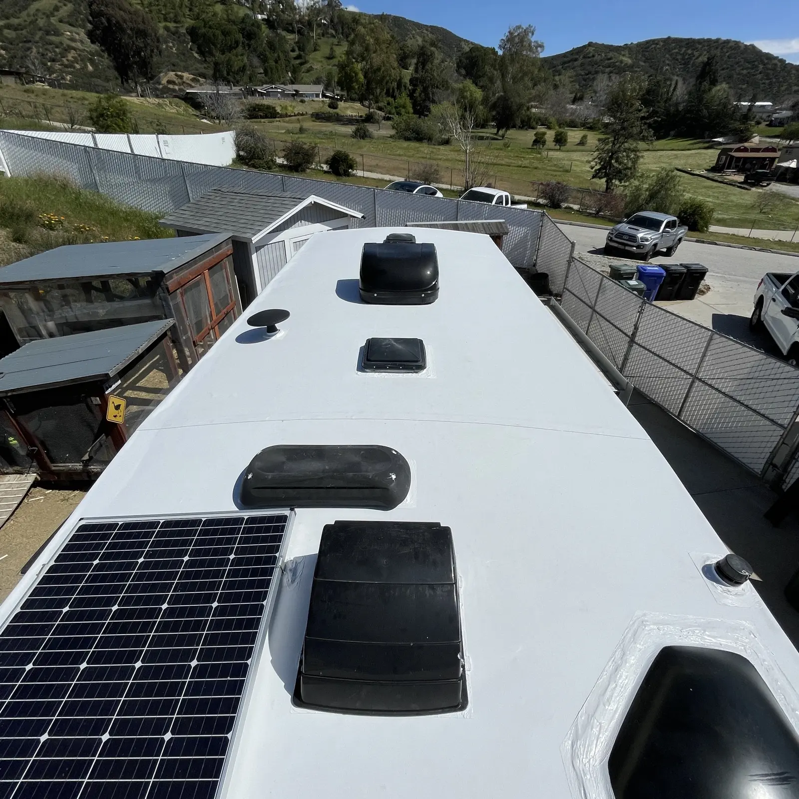 Finished TPO RV roof with resealed vents, skylight, and air conditioner at a driveway in Southern California